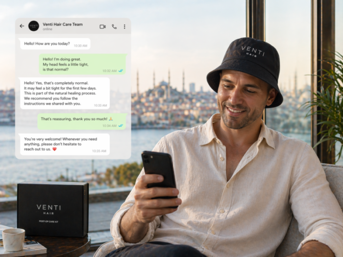 A smiling patient wearing a Venti Hair bucket hat and chatting with the Venti Hair care team on WhatsApp with a beautiful Istanbul view.
